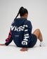 Rear view of female model seated in the RUDIS USA Wrestling Map fleece hoodie in Navy, featuring oversized WRESTLING lettering and RUDIS Wrestling A Way of Life back detail.