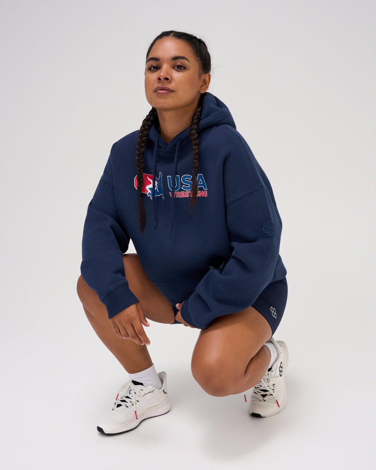 Female model wearing the RUDIS USA Wrestling Script Relaxed Comfort Fleece Hoodie in Navy, featuring a red, white and blue USA Wrestling chest logo, drawstring hood and relaxed fit.
