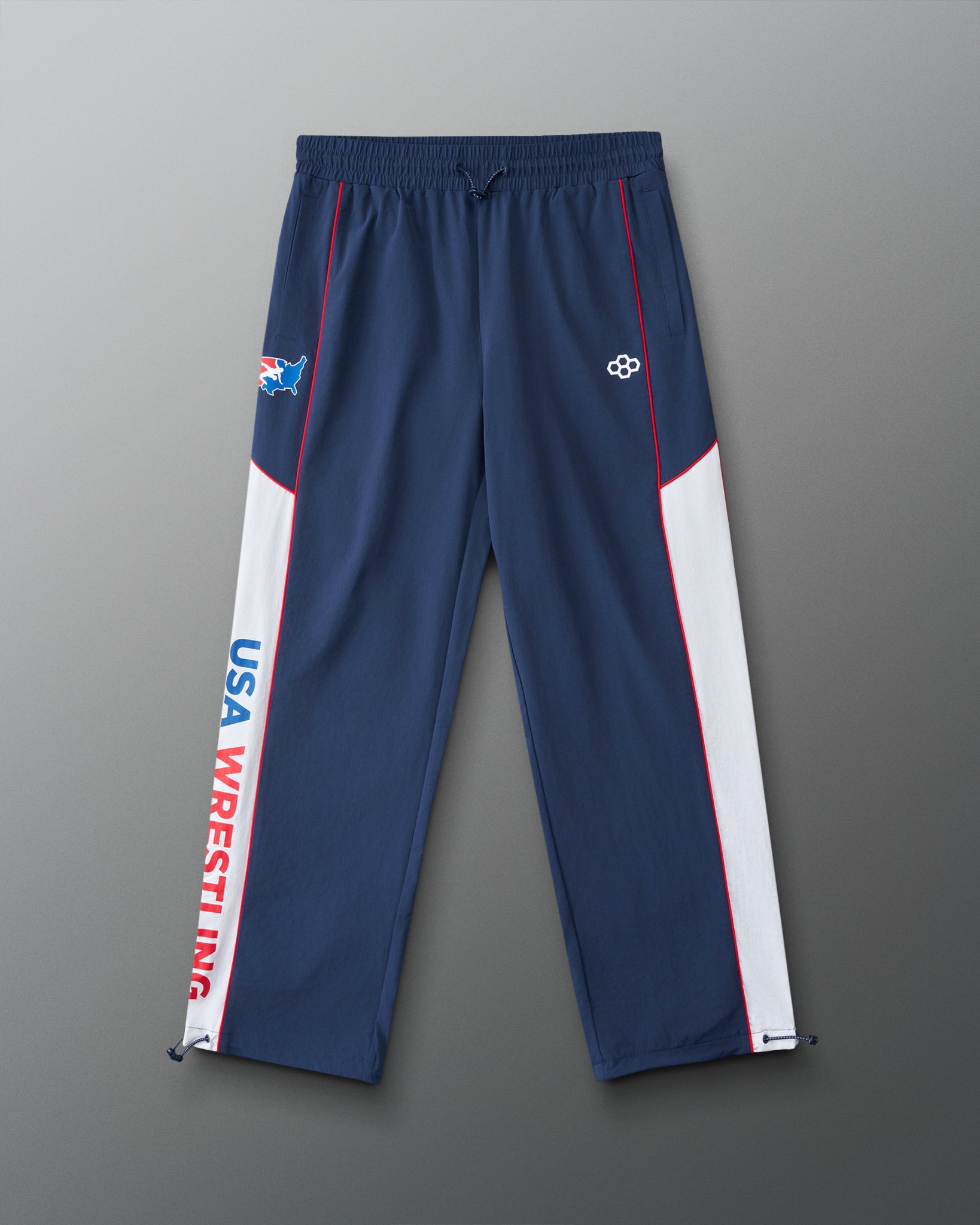 Front view of the RUDIS USA Wrestling Movement Podium Pants in navy, featuring white side panels, red piping, USA Wrestling graphics, RUDIS logo, and adjustable ankle cords.