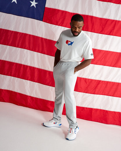 RUDIS USA Wrestling Luxe Terry Jogger in Lunar worn with a USA Wrestling T-shirt and training shoes in front of an American flag.