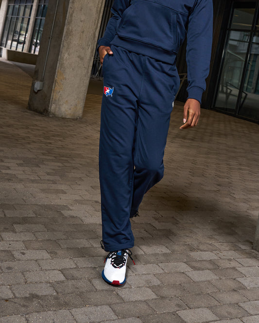 Person wearing a blue tracksuit with a logo on a paved ground.