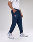 Person wearing navy tracksuit pants with a 'USA Wrestling' logo and white sneakers on a light gray background