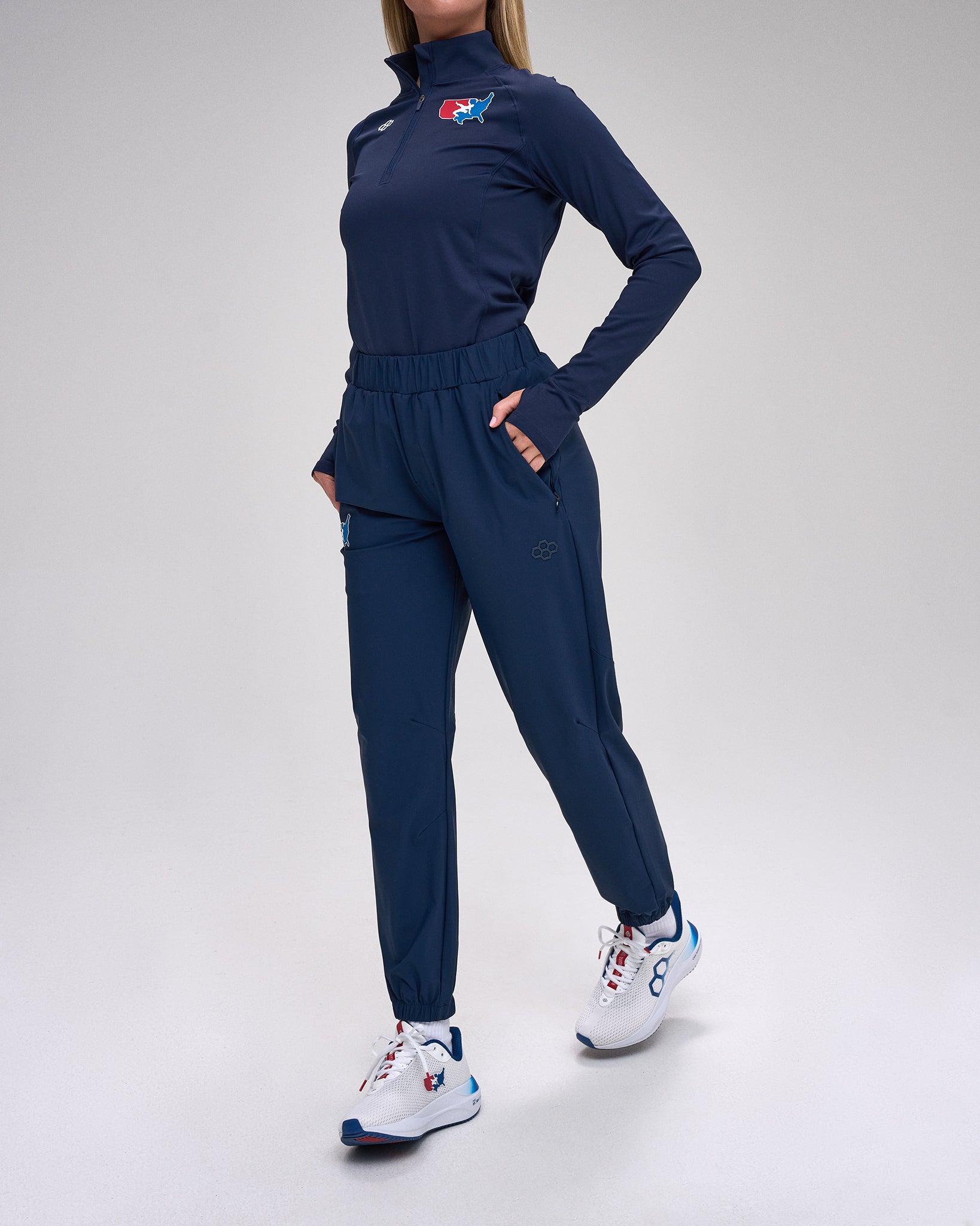 Person wearing a navy tracksuit with a 'USA Wrestling' logo on a white background
