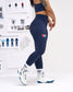 Person wearing navy leggings with a logo, white sneakers, and socks in a room with shelves displaying various items.