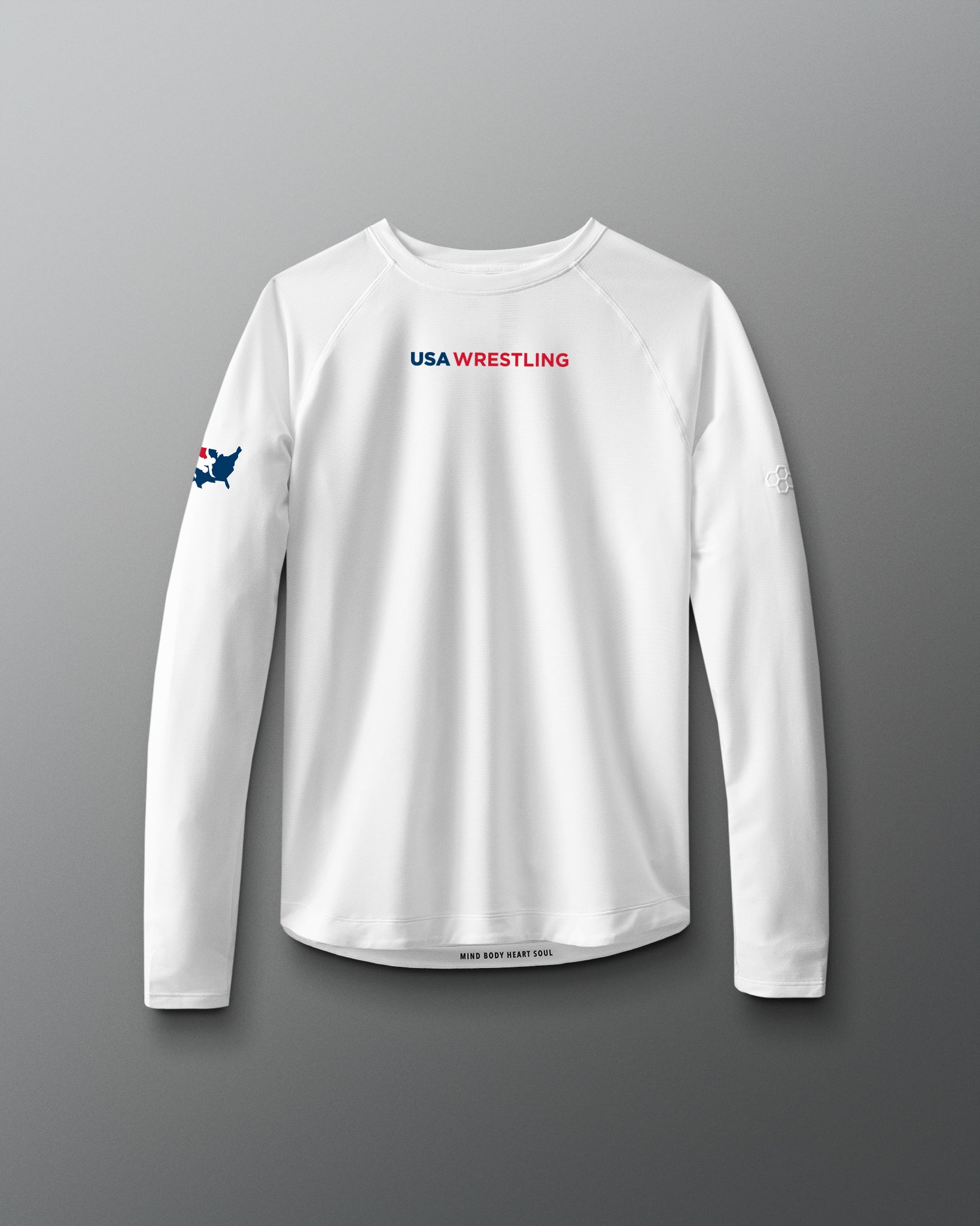 A long sleeve white t-shirt with 'USA WRESTLING' text and a small graphic on the chest area, displayed against a red to blue gradient background.