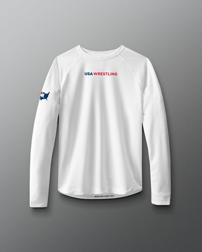A long sleeve white t-shirt with 'USA WRESTLING' text and a small graphic on the chest area, displayed against a red to blue gradient background.