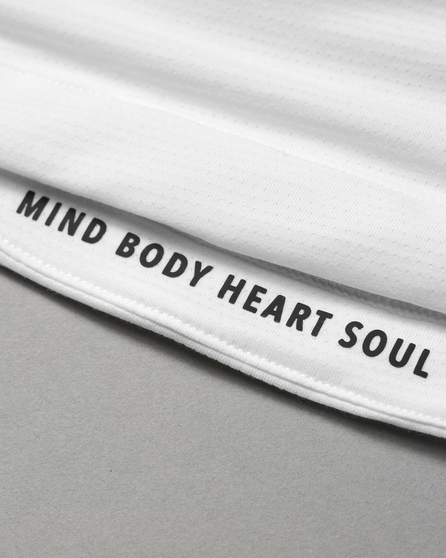 Close up of MIND BODY HEART SOUL black text on white garment background