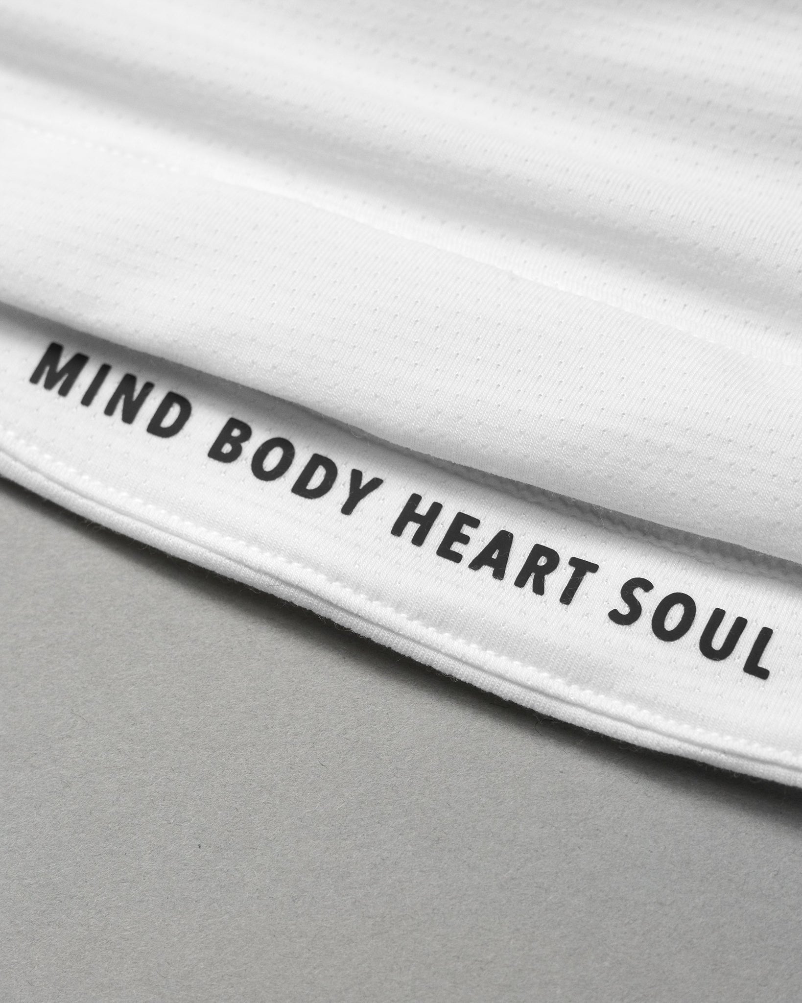 Close up of MIND BODY HEART SOUL black text on white garment background