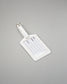 A white leather luggage tag with a silver metal buckle, featuring blank lines for name, address, and contact information, set against a solid gray background.