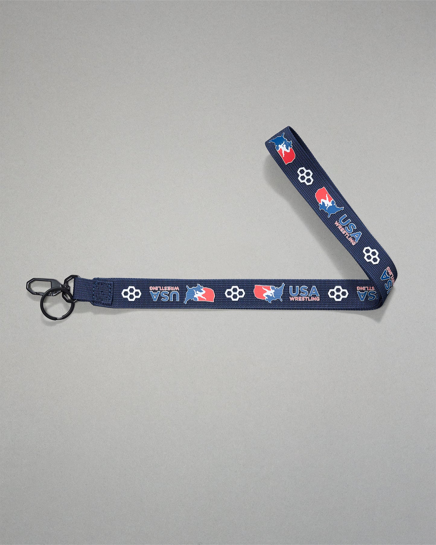 Navy USA Wrestling lanyard with repeating USA Wrestling logos and RUDIS honeycomb icons, featuring a woven polyester strap, black metal key clip, and key ring for keys, badges, or accessories.