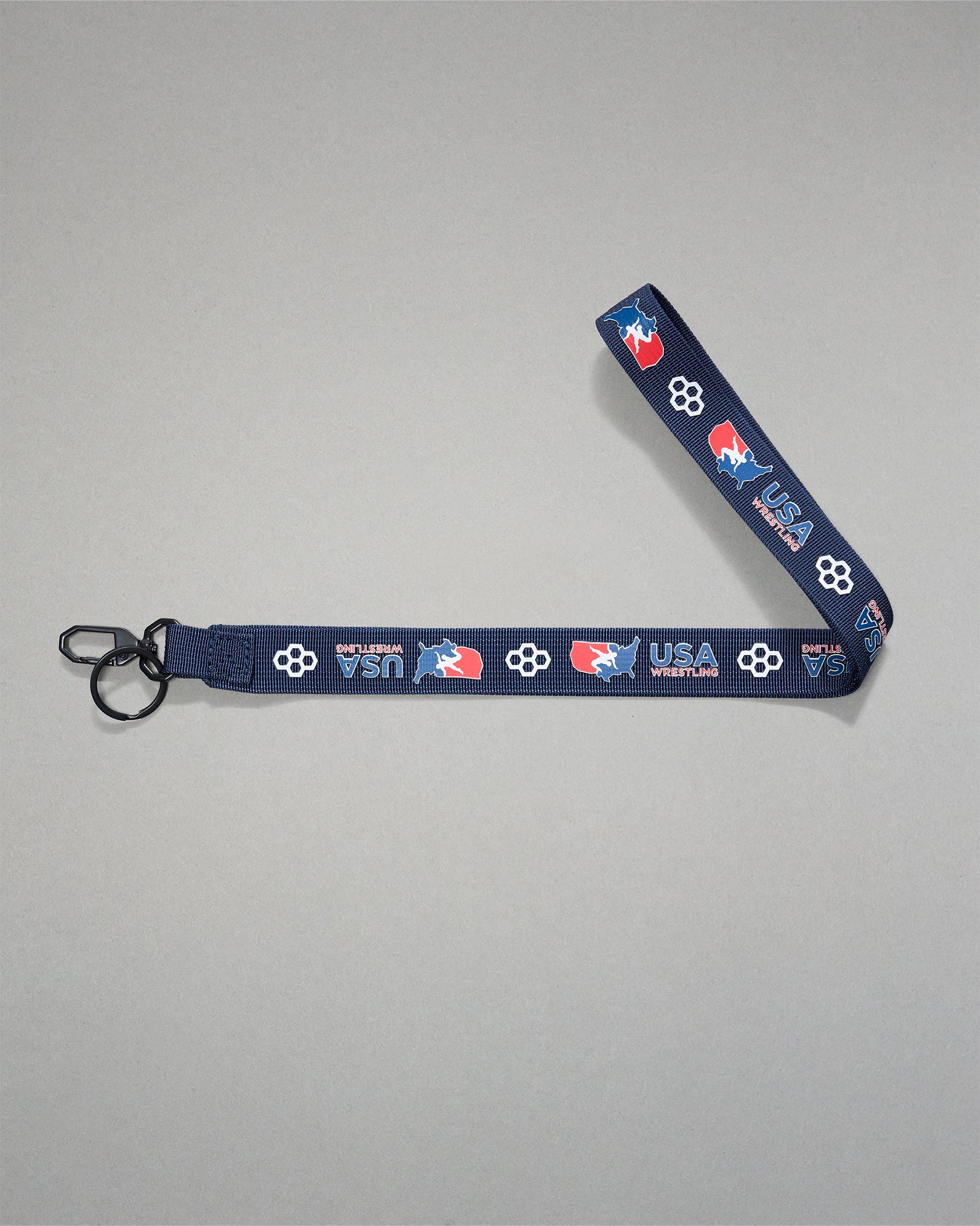 Navy USA Wrestling lanyard with repeating USA Wrestling logos and RUDIS honeycomb icons, featuring a woven polyester strap, black metal key clip, and key ring for keys, badges, or accessories.