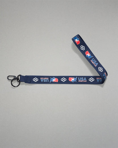 Navy USA Wrestling lanyard with repeating USA Wrestling logos and RUDIS honeycomb icons, featuring a woven polyester strap, black metal key clip, and key ring for keys, badges, or accessories.