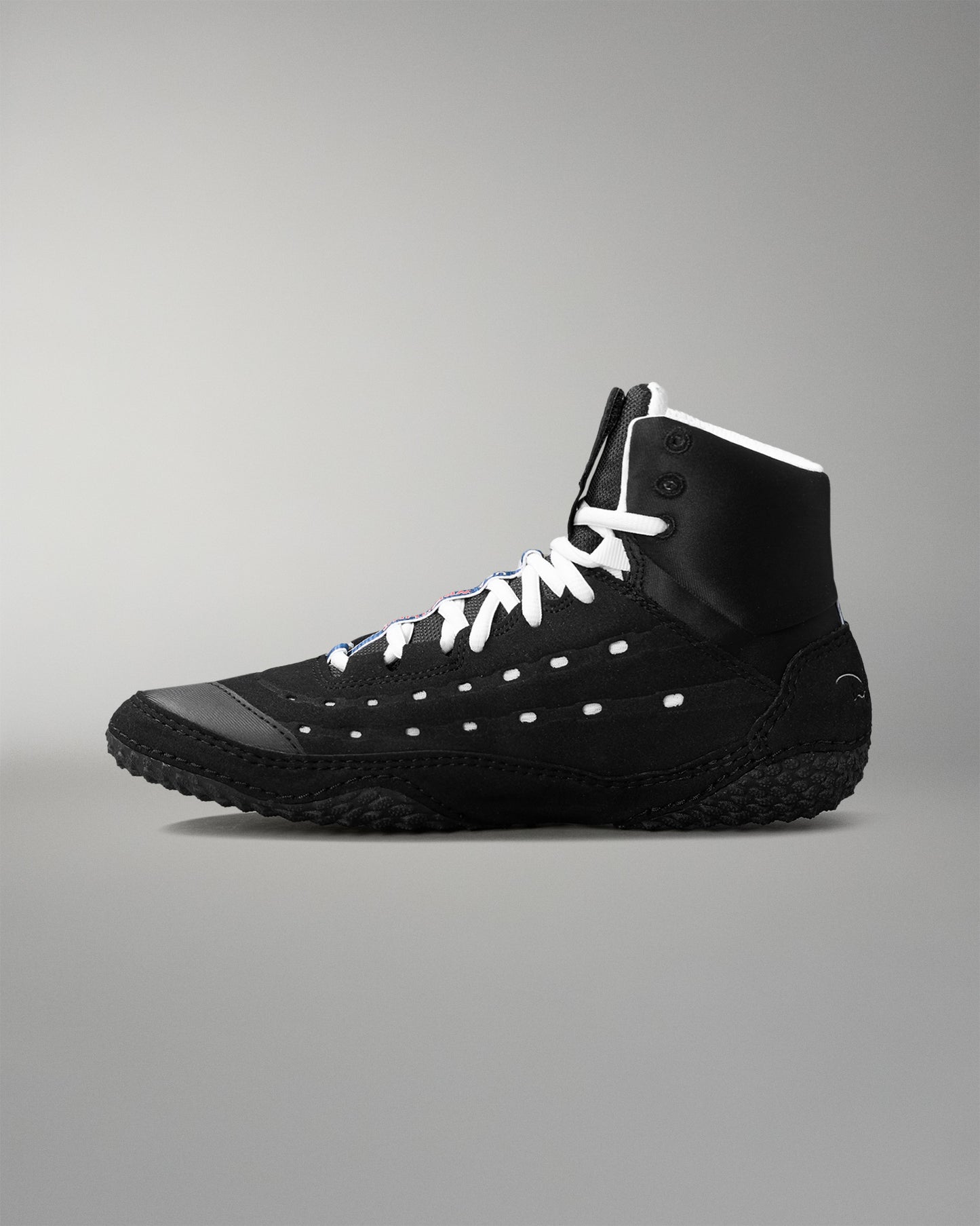 Black wrestling shoe with white laces on a gray background