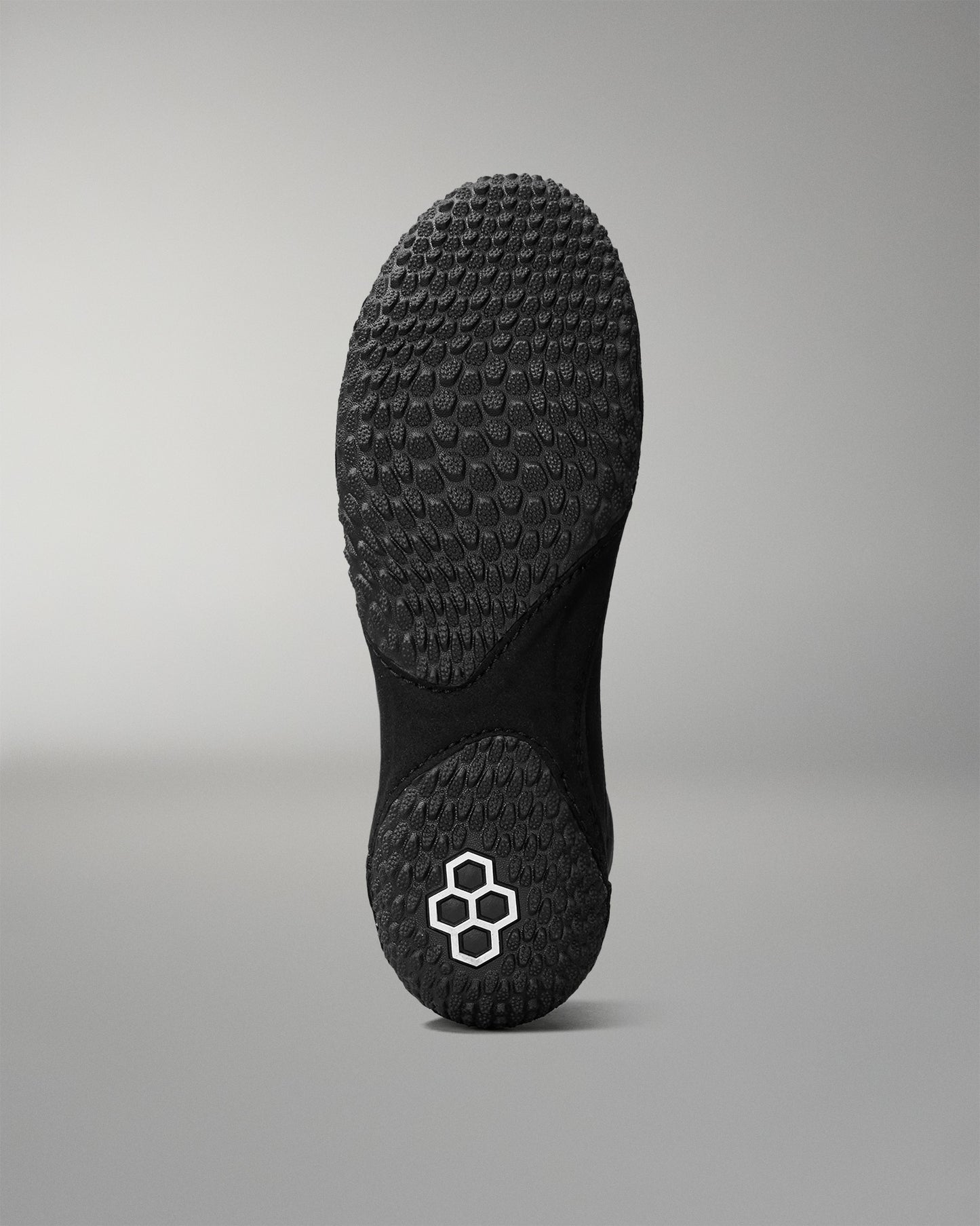 Black sole of a wrestling shoe with a brand logo on a gray background