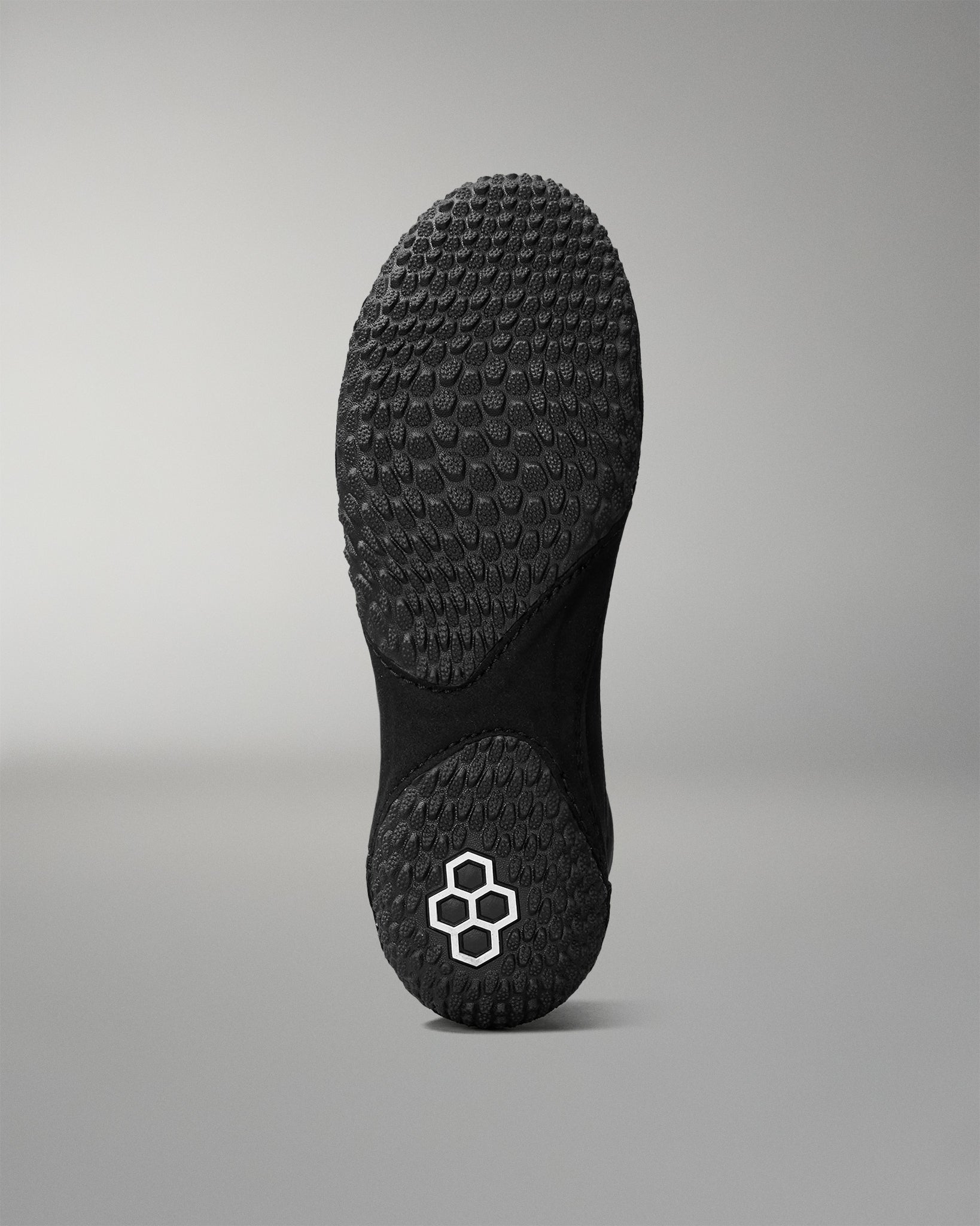 Black sole of a wrestling shoe with a brand logo on a gray background