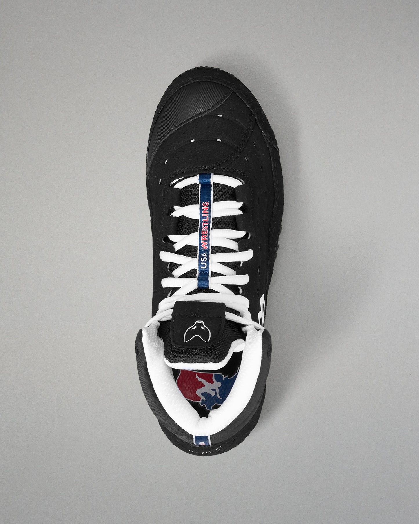 Black wrestling shoe with white laces on a gray background
