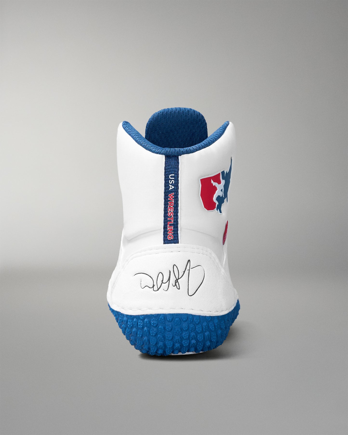 White wrestling shoe with blue sole and red and blue logo on a gray background