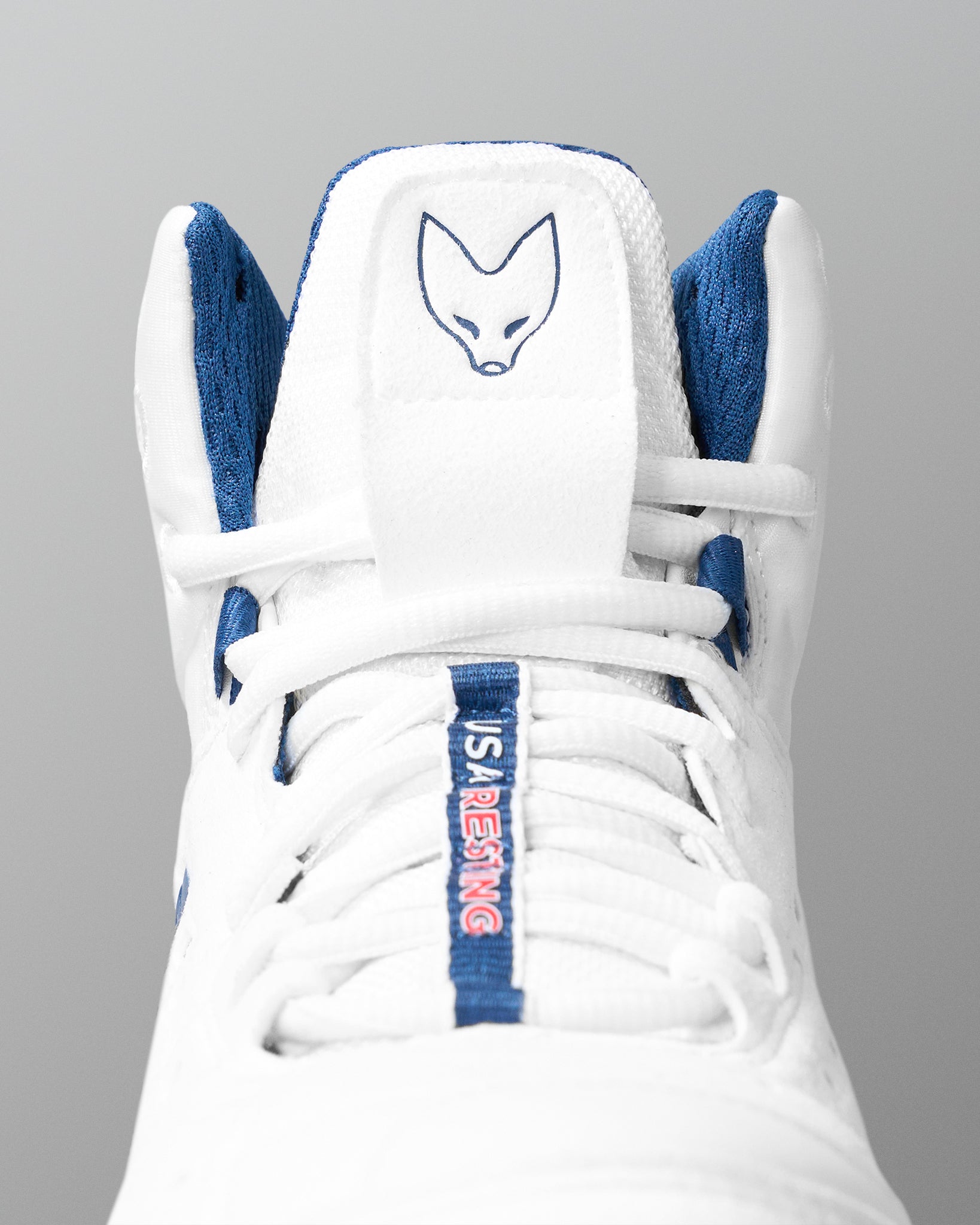 White wrestling shoe with blue accents and a logo on a gray background