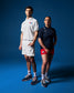 A male and a female wrestler standing side by side wearing USA Wrestling polos in white and blue colors, with the male in the foreground and the female in the background.