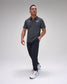 Man wearing a dark gray polo shirt with a 'USA Wrestling' logo and dark pants on a light gray background
