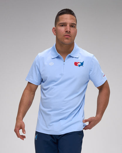 Man wearing a light blue polo shirt with a 'USA Wrestling' logo on a gray background