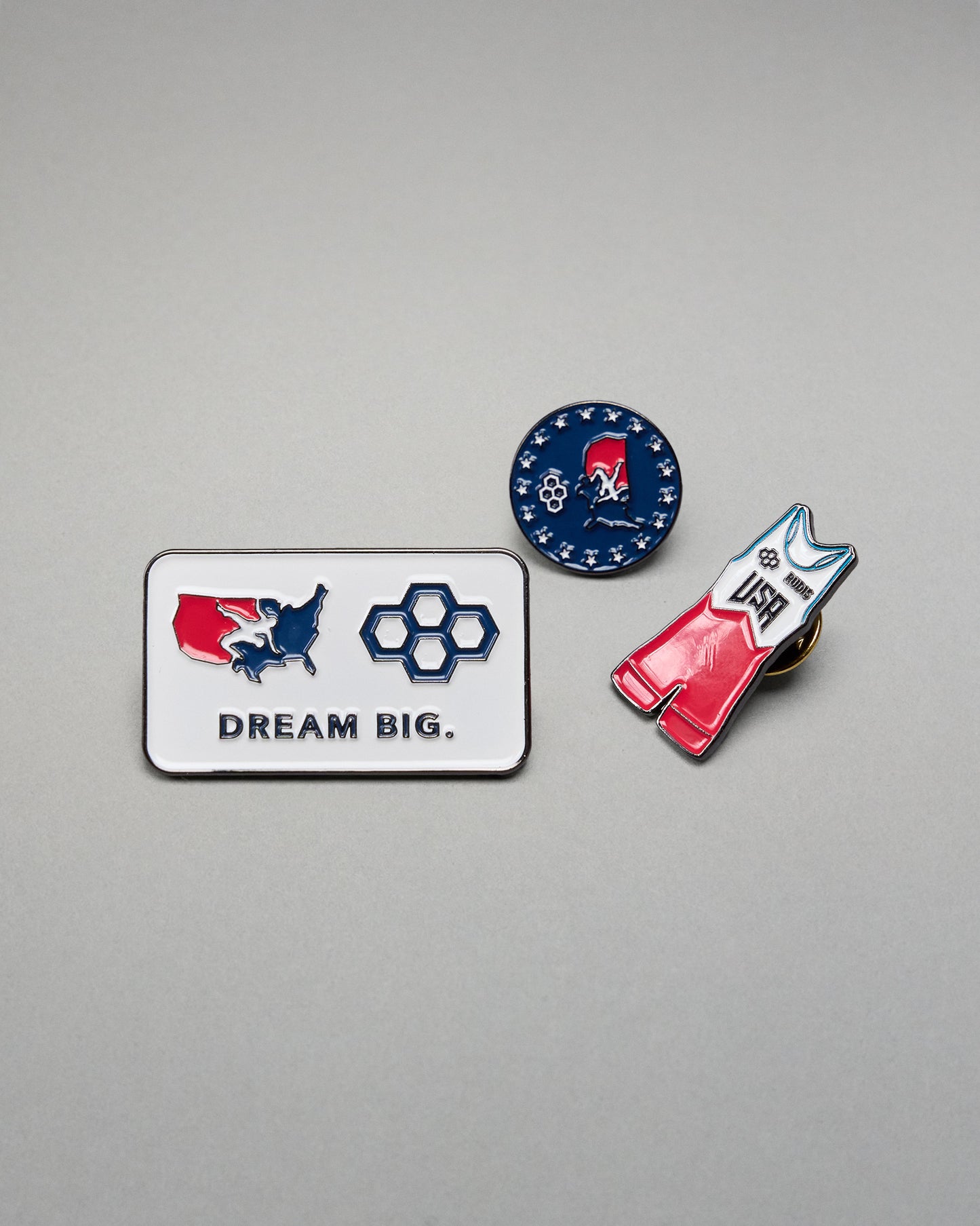 Three pins with different designs on a gray background