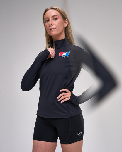 Woman wearing a black long-sleeve athletic top with a 'USA Wrestling' logo on a gray background