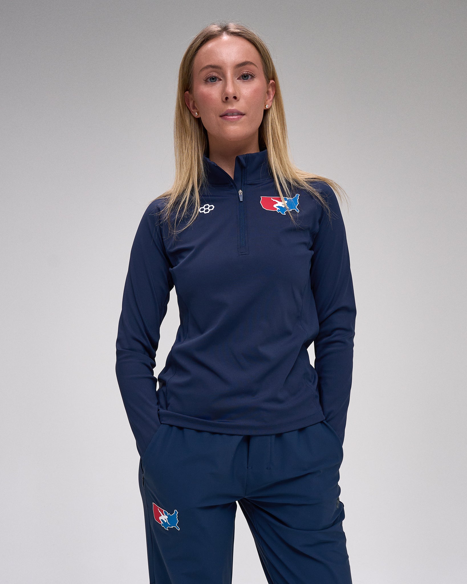 Person wearing a navy tracksuit with 'USA Wrestling' and 'RUDIS' logos on a gray background