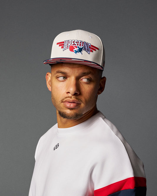 Man wearing a cap with 'Wrestling' design on a gray background