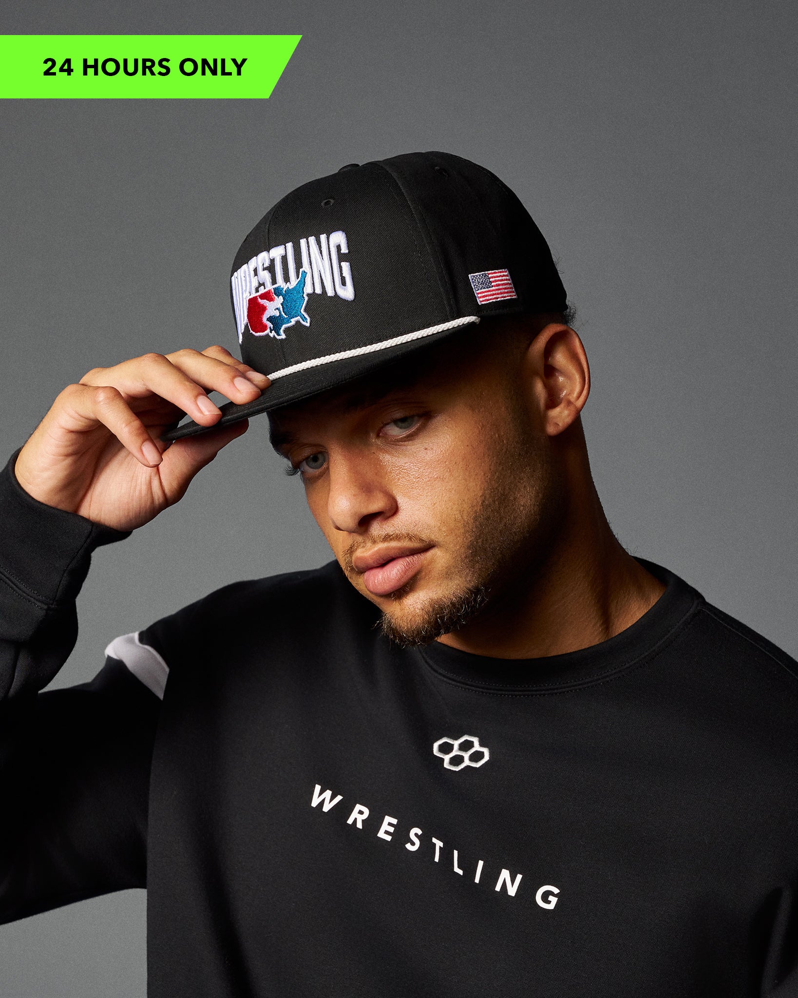 Man wearing a black cap and black 'Wrestling' sweatshirt on a gray background
