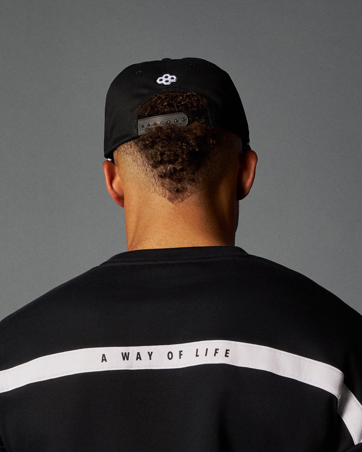 Person wearing a black cap and black shirt with 'A Way of Life' text on a gray background