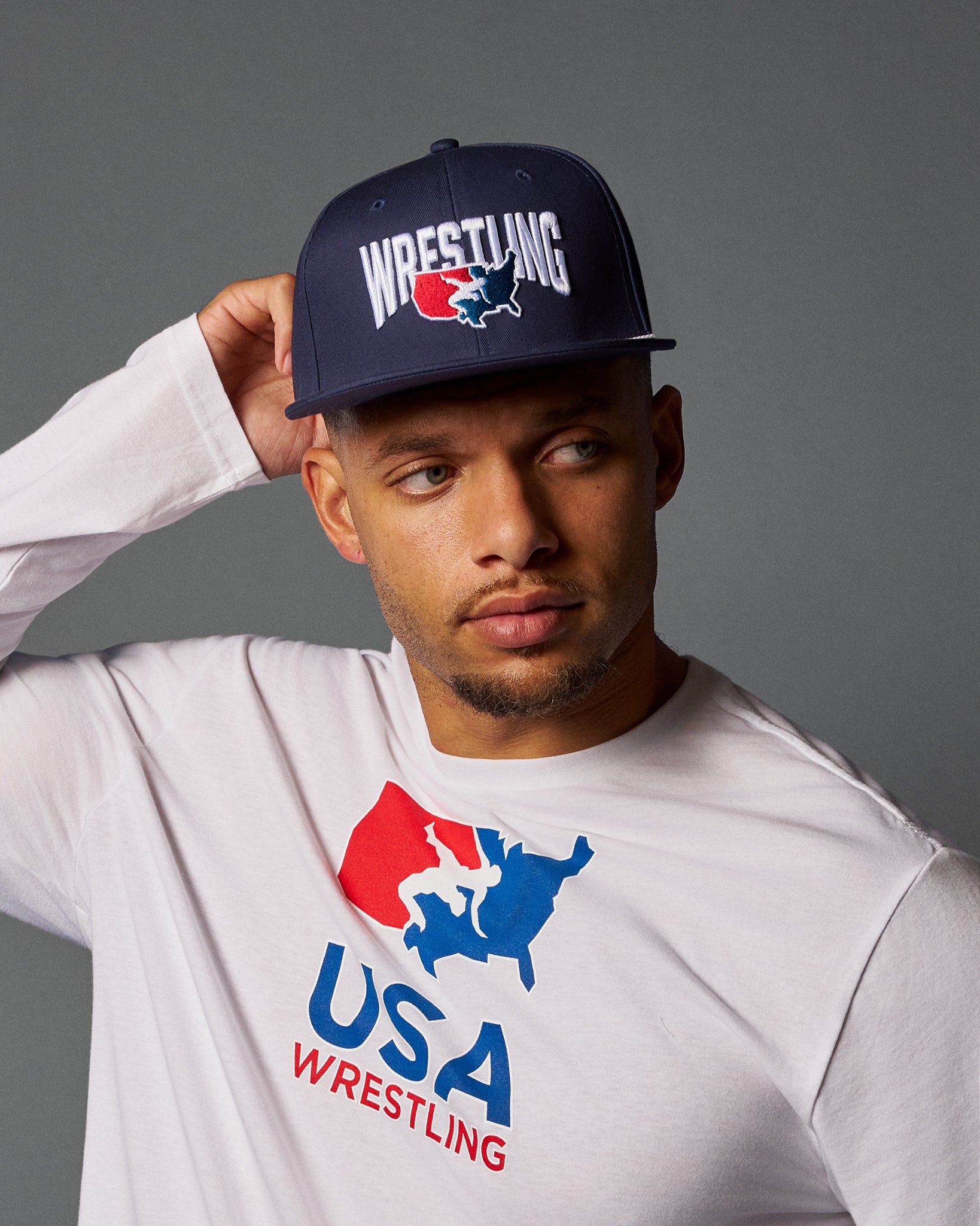 Person wearing a USA Wrestling cap and t-shirt against a gray background