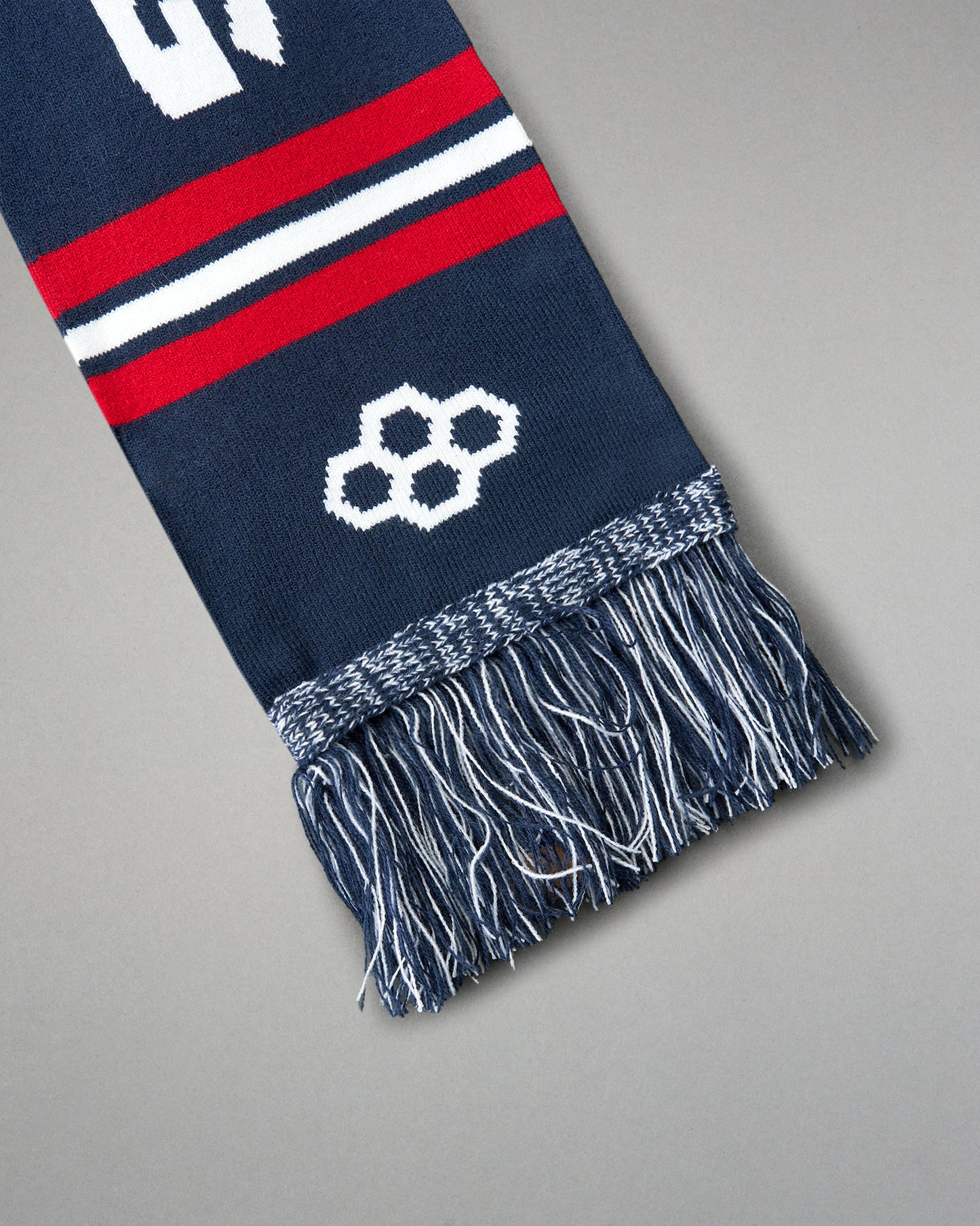 Navy blue scarf with red and white stripes and a geometric pattern on a gray background