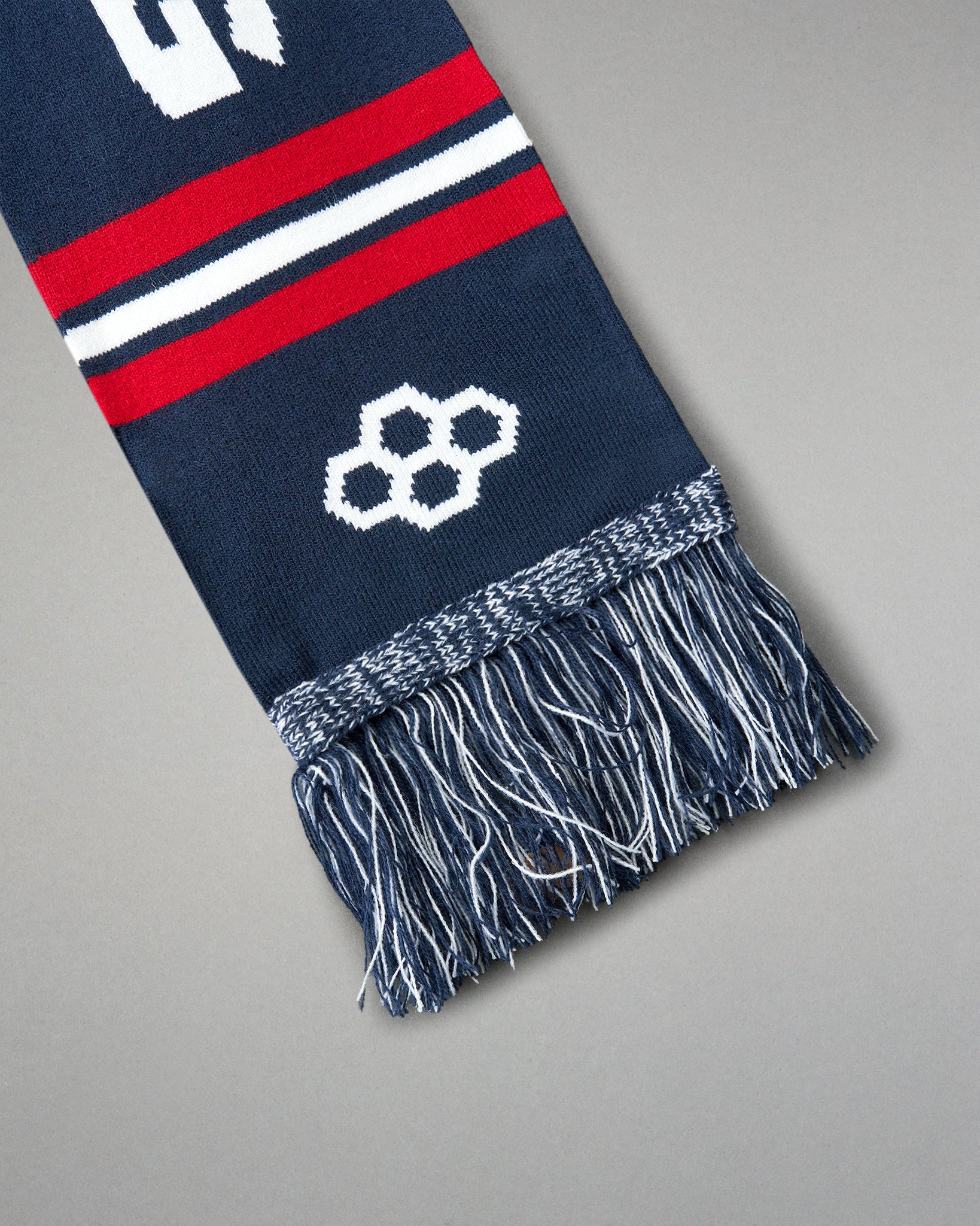 Navy blue scarf with red and white stripes and a geometric pattern on a gray background