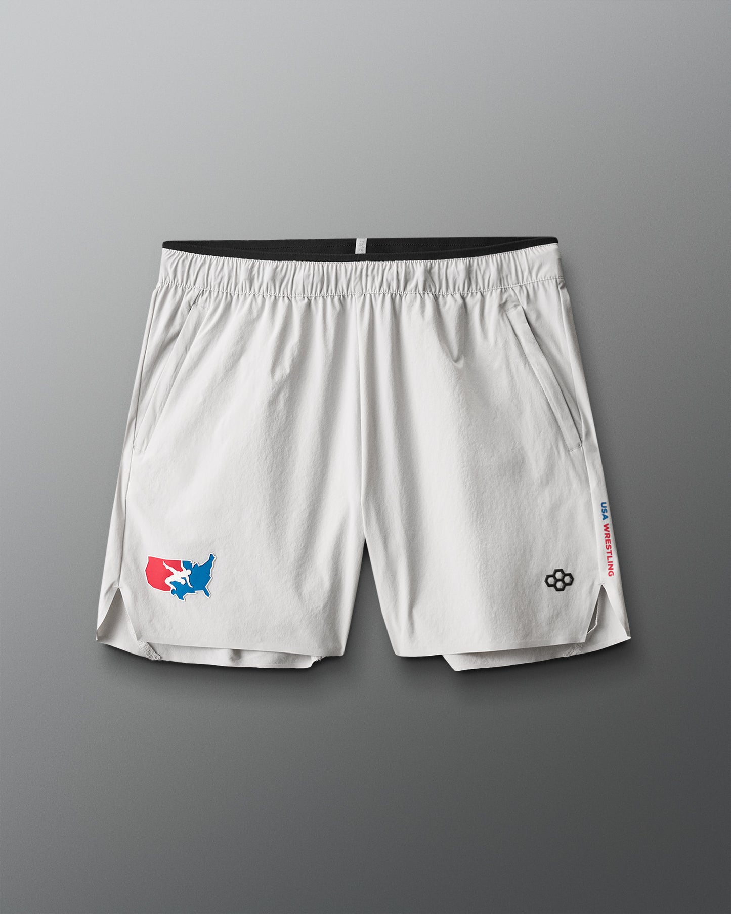 White athletic shorts with USA Wrestling logos on a gray background