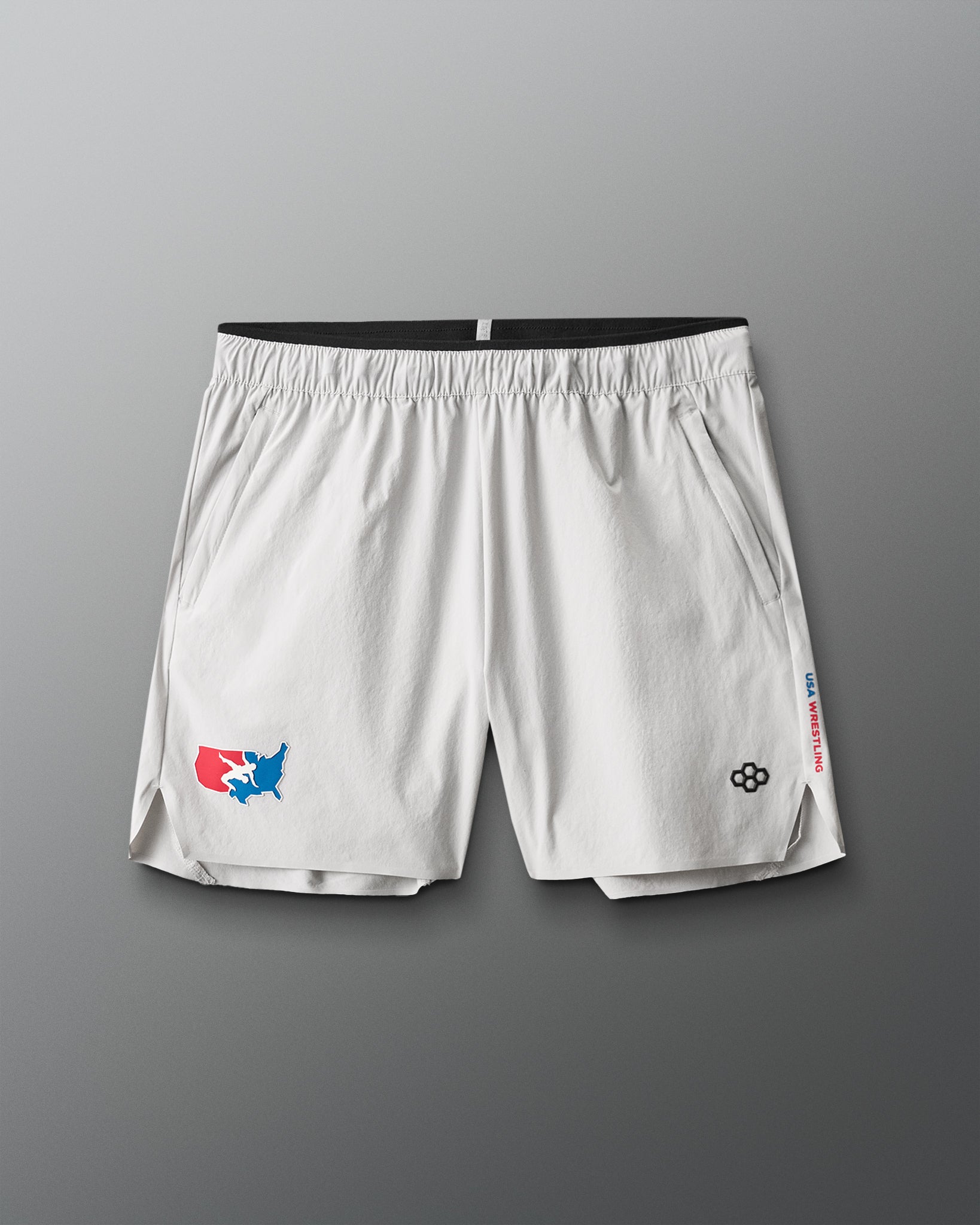 White athletic shorts with USA Wrestling logos on a gray background