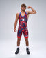 A man modeling a red and blue patterned Wrestling singlet with a USA Wrestling  graphic on the chest, standing against a light gray studio background.