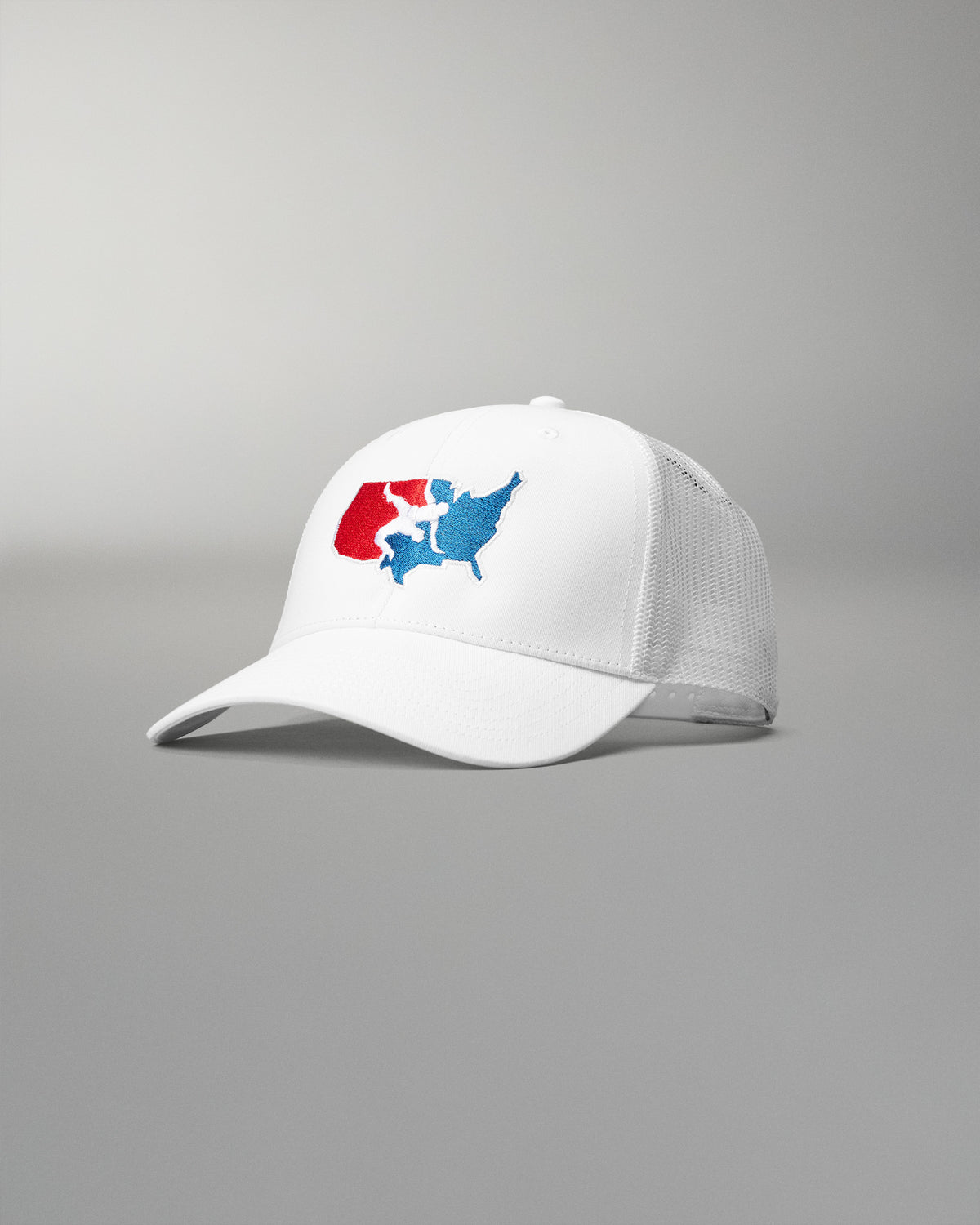 Front angled view of the RUDIS USA Wrestling Logo Bridge Trucker Hat in White, featuring an embroidered red, white and blue USA Wrestling logo, curved brim and white mesh panels.
