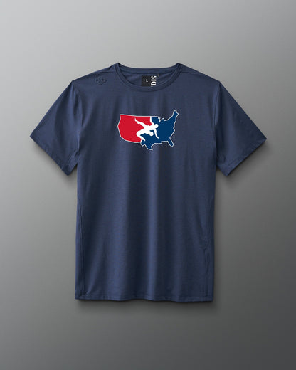 A navy blue short-sleeve athletic T-shirt is displayed against a gray background. Centered on the chest is a red, white, and blue USA Wrestling logo shaped like the continental United States, featuring two wrestlers in action. The shirt has a modern athletic fit.