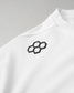 A close-up of the upper shoulder area of a white athletic shirt. The focus is on a raised black RUDIS hex logo made of six interlocking hexagons, located near the front collar. The fabric has a smooth texture with visible stitching along the shoulder seam.