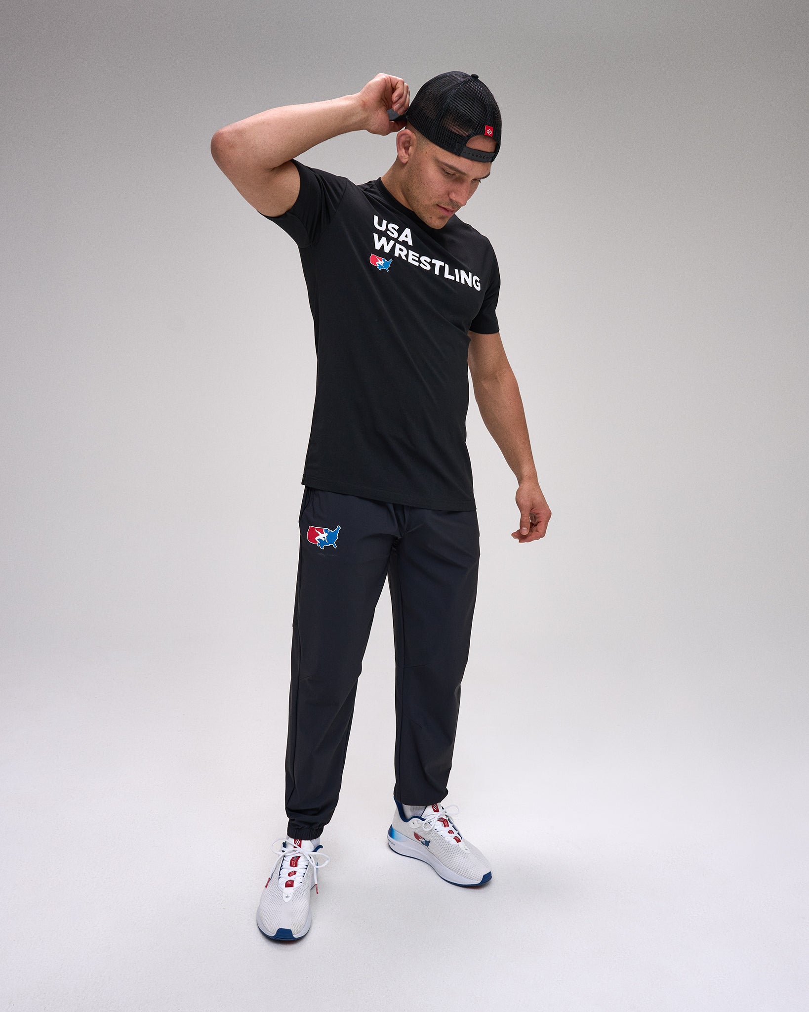 Person wearing a black 'USA Wrestling' t-shirt and pants on a gray background
