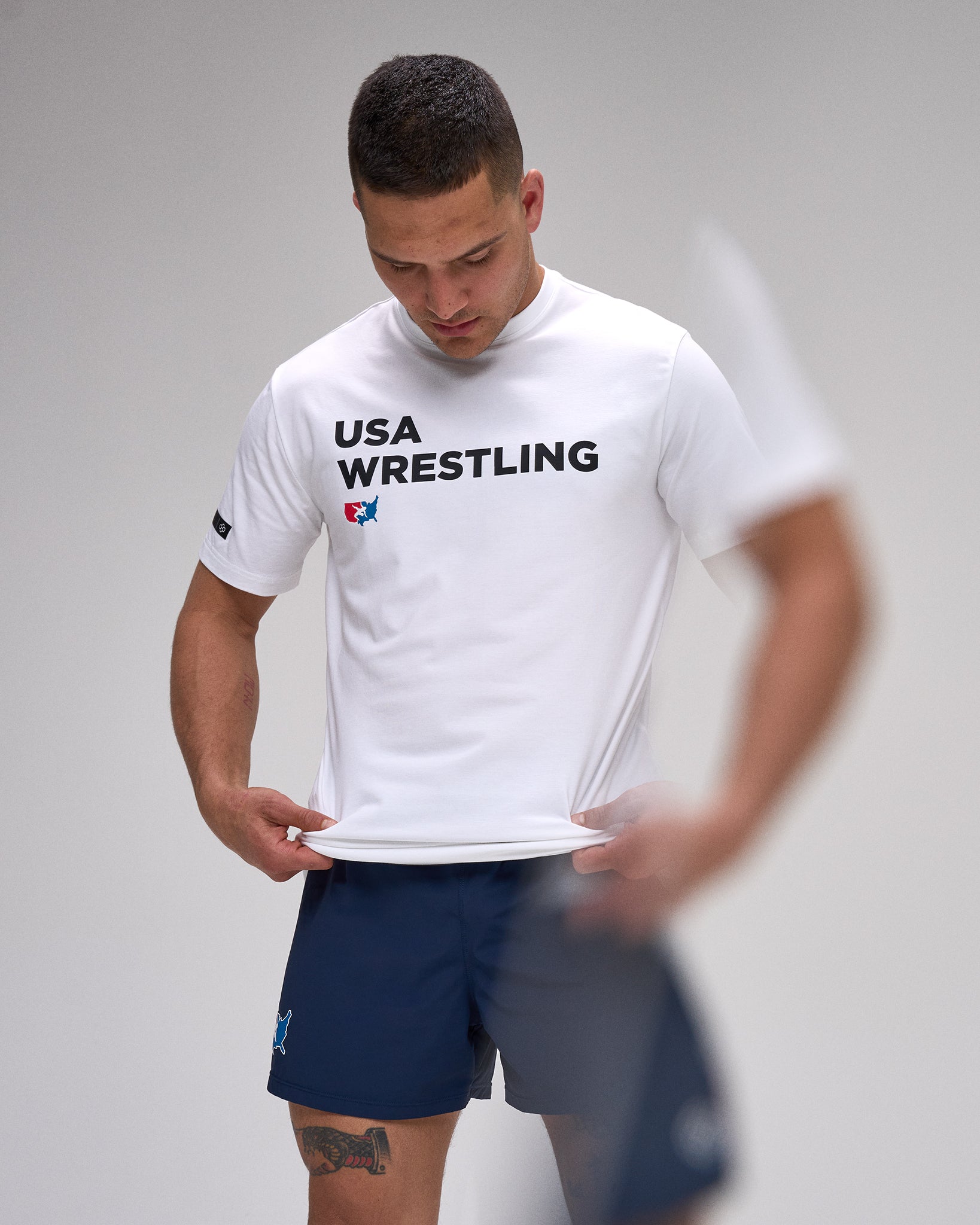 Person wearing a white 'USA Wrestling' t-shirt on a plain background
