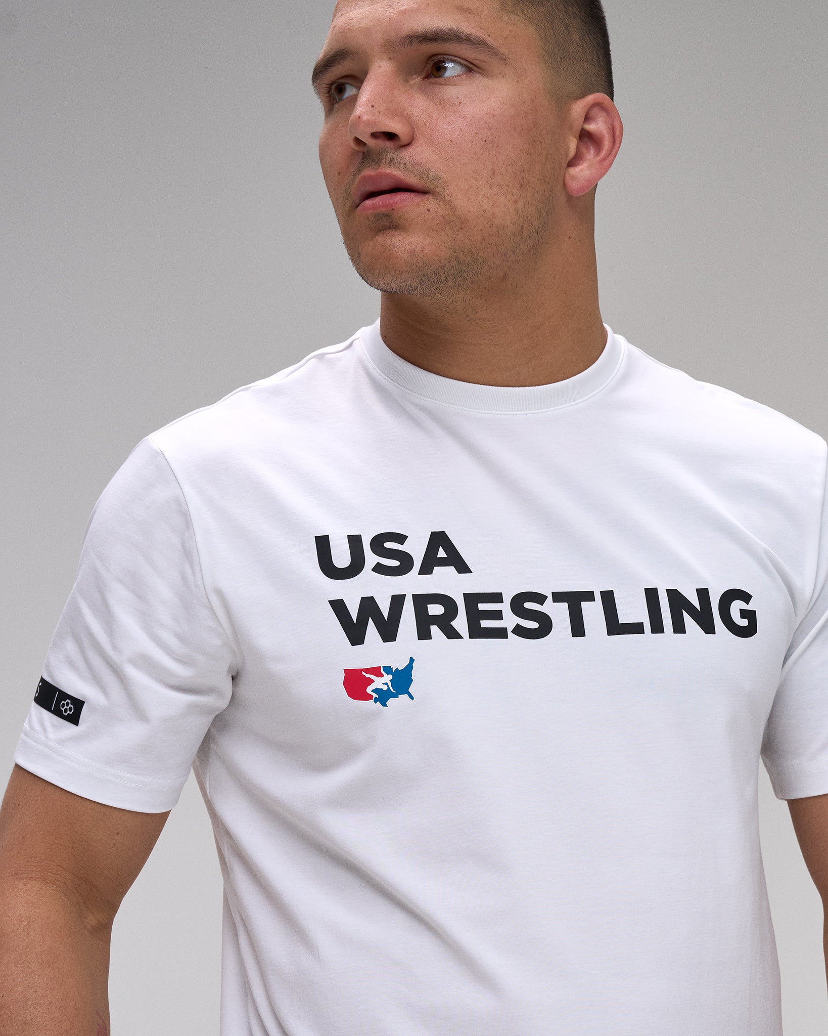 Man wearing a white 'USA Wrestling' t-shirt against a gray background