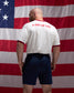 Man wearing a white shirt with 'A Way of Life' text in red, standing in front of an American flag.