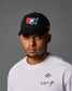 Man wearing a black cap with a logo and a white t-shirt with text on a gray background