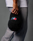 Person holding a black cap with a logo against a gray background