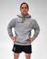 A man modeling a heather gray pullover hoodie with 'UNITED WORLD WRESTLING' printed across the chest in black and orange, paired with black athletic shorts, against a light gray studio background.