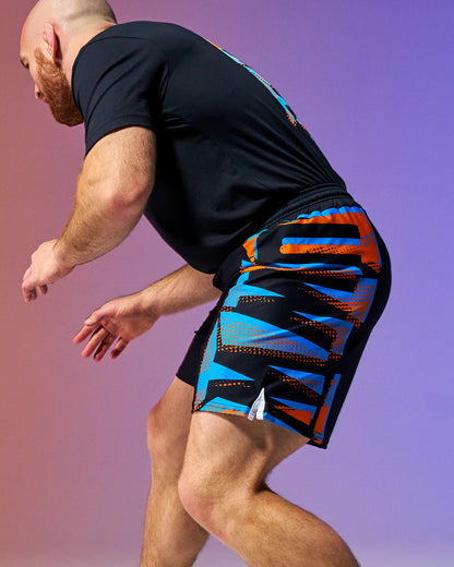 Person wearing black athletic shirt and colorful shorts on a gradient background