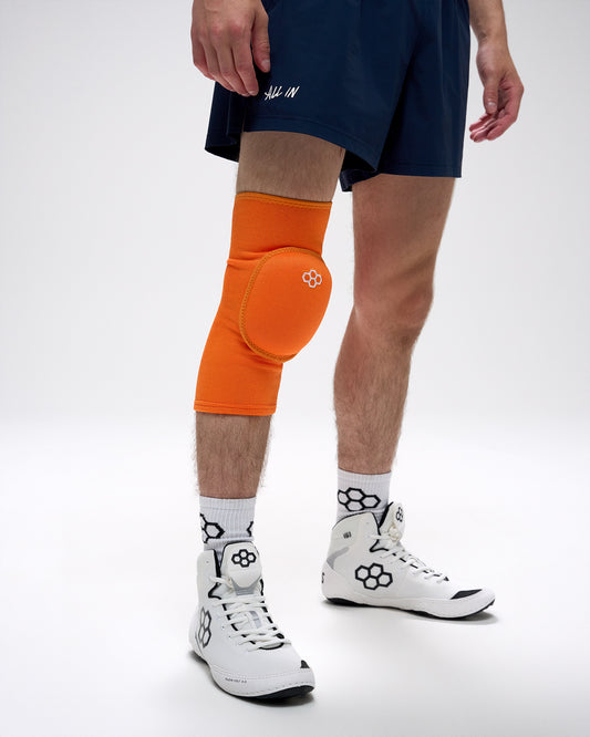 Person wearing an orange knee pad on a white background
