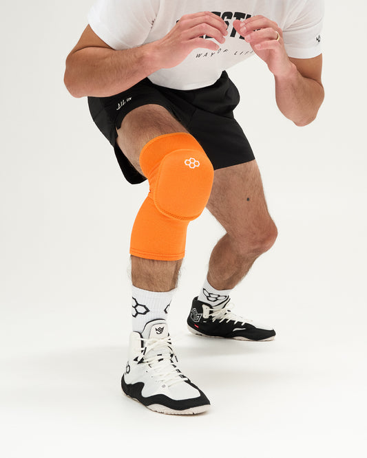 Person wearing an orange knee pad on a white background
